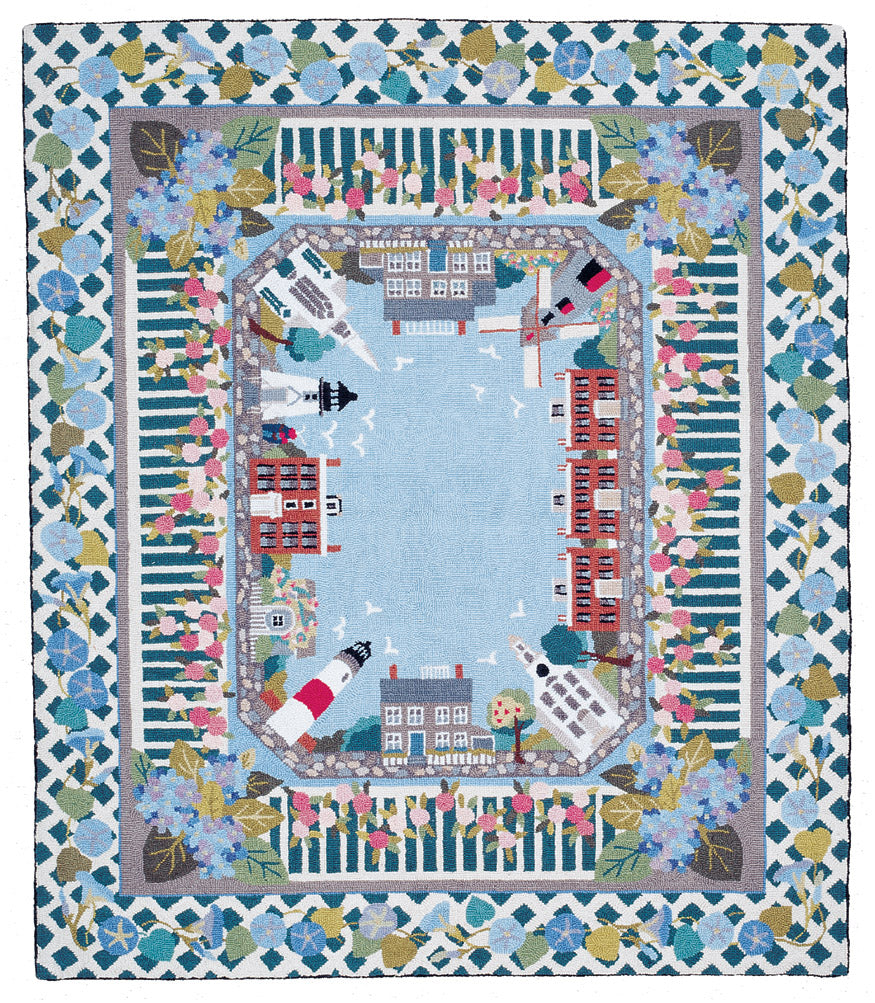 Decorative quilt with a coastal scene featuring buildings, boats, and flowers.