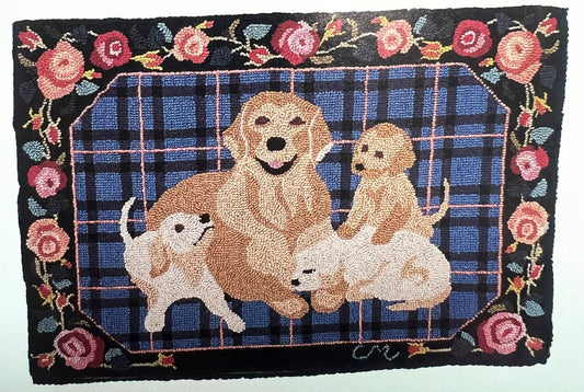 A rectangular hand-hooked rug featuring a family of golden retriever dogs in front of a blue plaid background, surrounded by a black border with pink roses and green leaves.