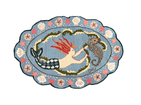 Decorative rug with mermaid and seahorse design on a blue background