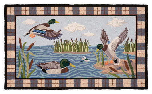 A rectangular hand-hooked rug featuring a marsh scene with three mallards, reeds, blue water, and a plaid border.