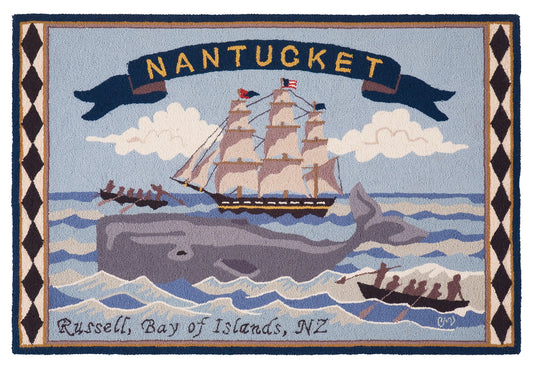 A hand-hooked rug featuring a Nantucket maritime scene with a large gray whale, a sailing ship, small boats, clouds, and a banner reading “NANTUCKET.” The bottom edge includes the text “Russell, Bay of Islands, NZ.