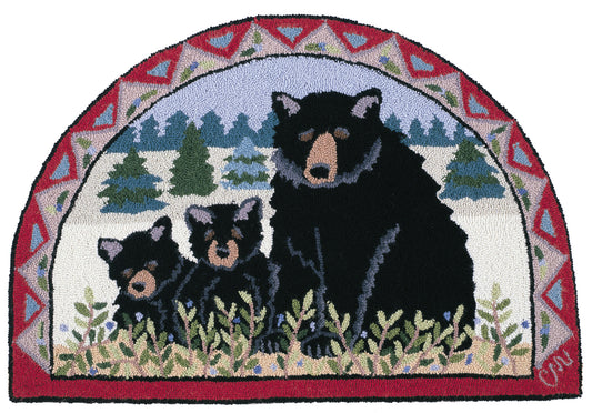 A semi-circular hand-hooked rug featuring a black bear and two cubs in a snowy forest scene, framed by a red, blue, and cream geometric border.