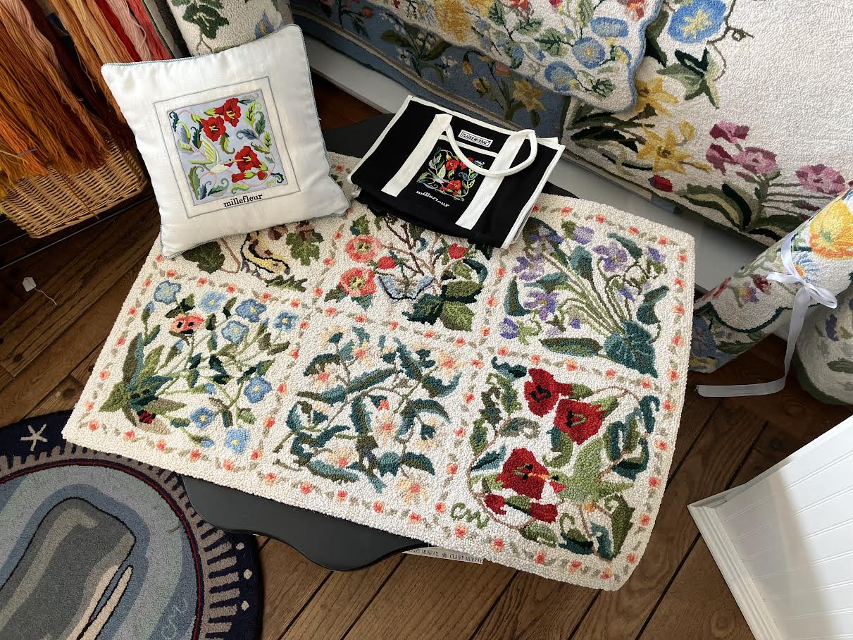Floral-patterned rug with embroidered design on a wooden floor, surrounded by decorative items.